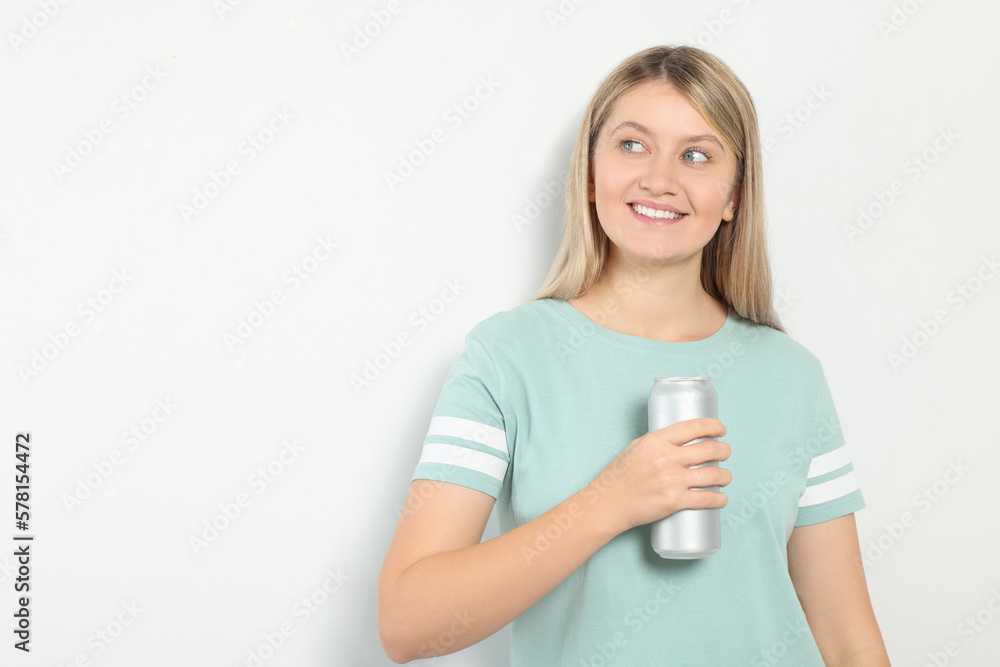 Beautiful happy woman holding beverage can on light background. Space for text Beautiful happy woman holding beverage can on light background. Space for text
