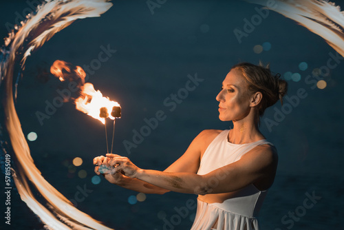 Caucasian woman dancing with fire in the water. Fire show at sea. Acrobatics on the beach. Yoga and relaxation at sunset. Spectacular circus performance. model body. High quality FullHD footage. 