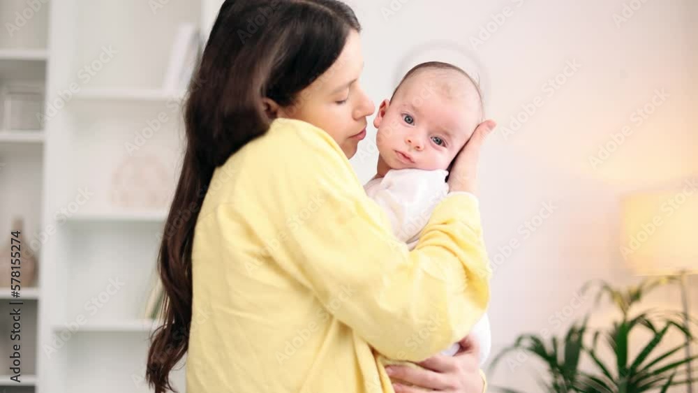 Portrait of adorable little baby infant in mother's hands and enjoying time together at home Mom holding her baby's hand gently and soothes the child with his pleasant voice indoors Portrait of adorable little baby infant in mother's hands and enjoying time together at home Mom holding her baby's hand gently and soothes the child with his pleasant voice indoors