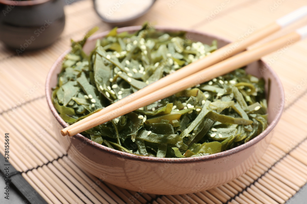 Fresh laminaria (kelp) seaweed in bowl and chopsticks on table, closeup Fresh laminaria (kelp) seaweed in bowl and chopsticks on table, closeup