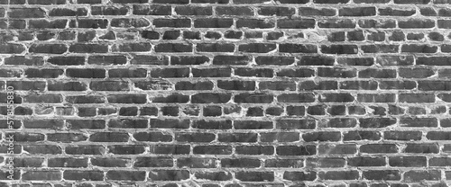 Grayscale backdrop with old realistic black brick wall. Minimal fragment of brickwall close-up. Minimalist monochrome background with wall of gray bricks in different shades. Simple wall texture.