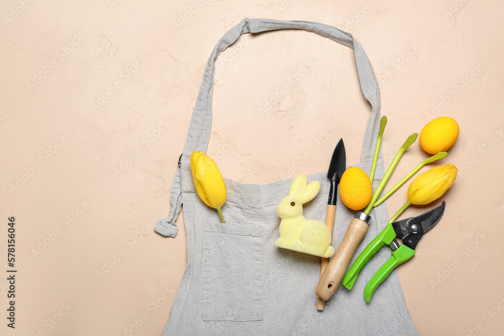 Gardener's tools with Easter eggs, rabbit and tulips on beige background