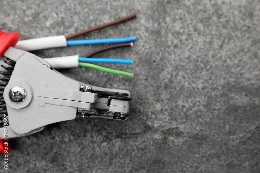 Professional cutters and cable with stripped wire on grey textured table, flat lay. Space for text Professional cutters and cable with stripped wire on grey textured table, flat lay. Space for text