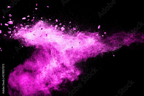 Split debris of stone exploding with pink dust powder against black background.