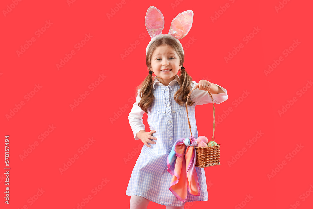 Cute little girl in bunny ears with basket of Easter eggs on red background Cute little girl in bunny ears with basket of Easter eggs on red background