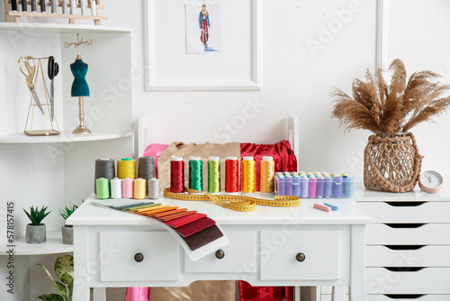 Interior of atelier with tailor's workplace, shelving unit and thread spools