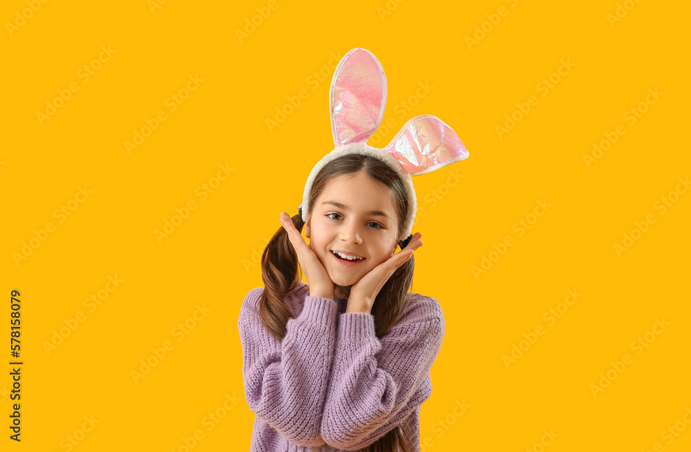 Happy little girl in bunny ears on yellow background Happy little girl in bunny ears on yellow background