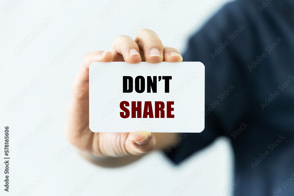 Don't share text on blank business card being held by a woman's hand with blurred background. Business concept to encourage not to share sensitive or fake information. Don't share text on blank business card being held by a woman's hand with blurred background. Business concept to encourage not to share sensitive or fake information.