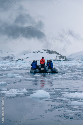 Zodiac boat filled with people, moving through Antarctic sea ice. 