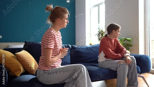 Stubborn teen girl daughter rejecting mother, upset worried woman mother dealing with difficult teenage child, mom and adolescent kid having conflict sitting together on sofa in living room at home photo