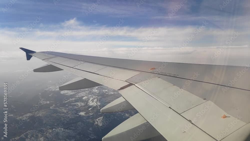 The wing of a passenger plane in flight. Passenger plane flying above the clouds. Airplane wing shot from the inside The wing of a passenger plane in flight. Passenger plane flying above the clouds. Airplane wing shot from the inside