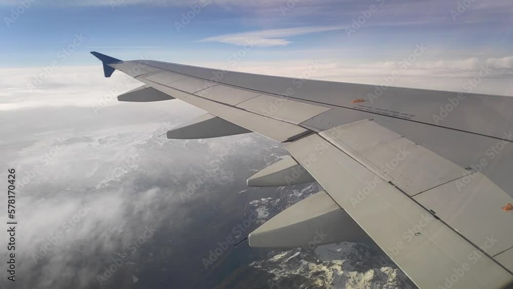 The wing of a passenger plane in flight. Passenger plane flying above the clouds. Airplane wing shot from the inside The wing of a passenger plane in flight. Passenger plane flying above the clouds. Airplane wing shot from the inside