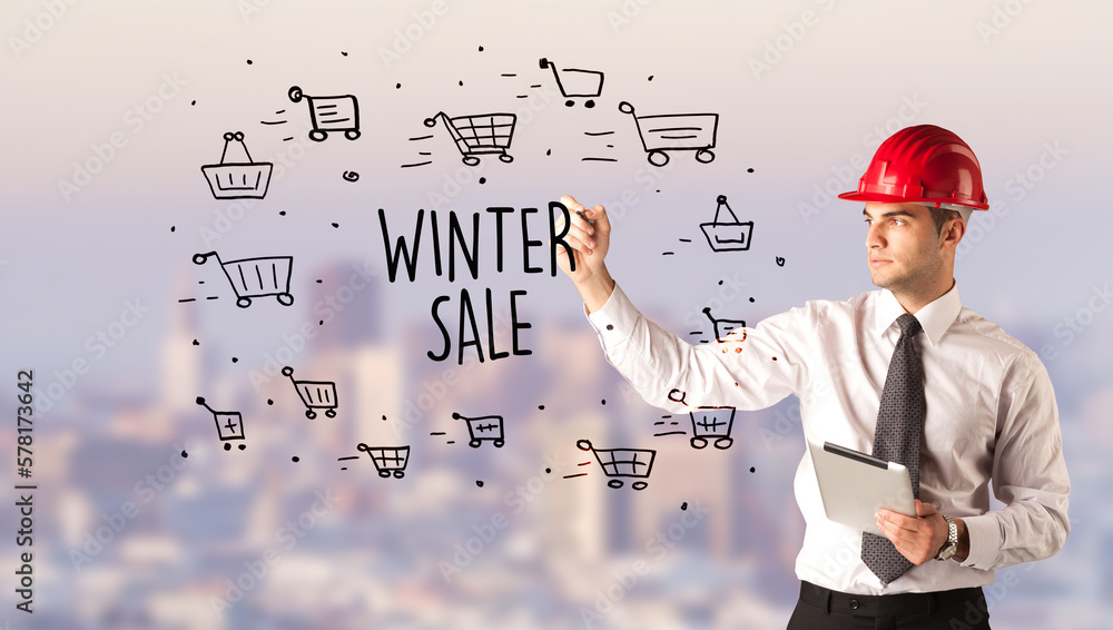 Young businessman with helmet drawing sale sign Young businessman with helmet drawing sale sign