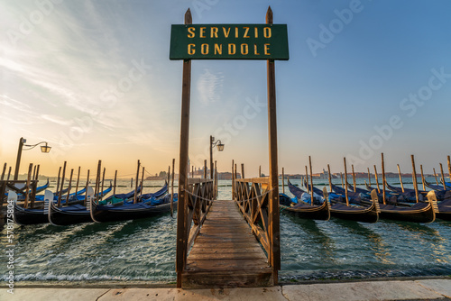 Billede på lærred Gondolas Moored Along Pier with Gondola Service Sign at Sunrise in Venice, Italy