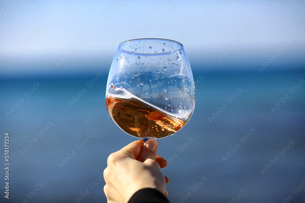a glass of port wine on the background of the sea, a hand with wine