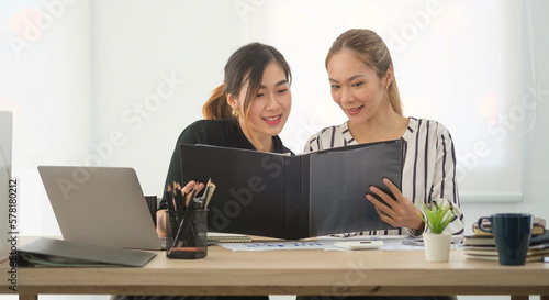 Two business women looking at reports and discussing project strategy, checking corporate plan.. © wattana