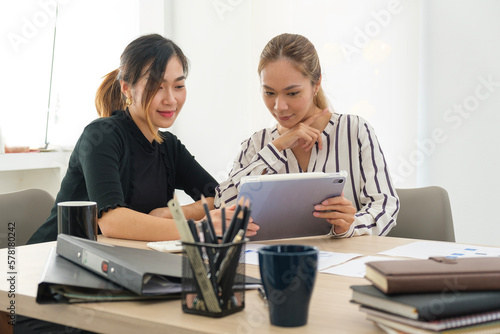 Image of female colleagues discussing results or presenting new project on laptop.