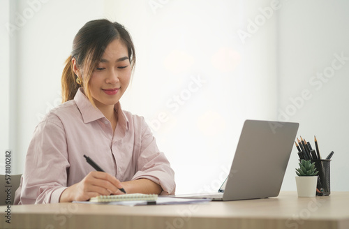Thoughtful asian businesswoman checking financial reports at her office desk..