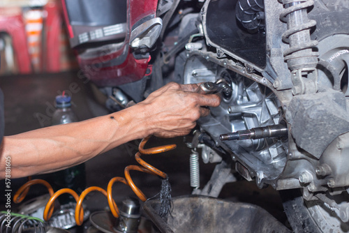 Motorcycle mechanic check the condition of Auto Transmission system or Clutch system of scooter at workshop. Repair and maintenance motorcycle concept.selective focus