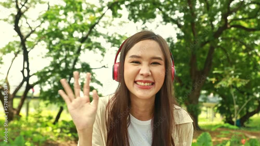 Asian female college student with headphones in a good mood stands explaining about the wonderful forest environment. Asian female college student with headphones in a good mood stands explaining about the wonderful forest environment.