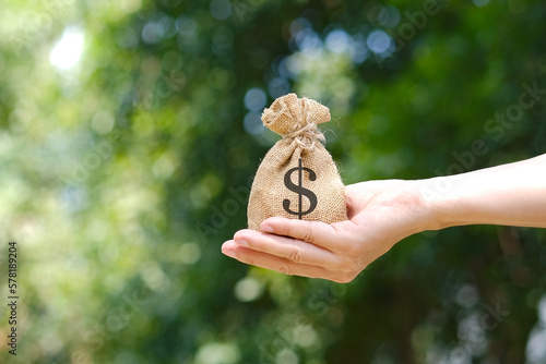 Man's hand holding a wallet and giving a bag of money, money saving and investment concept