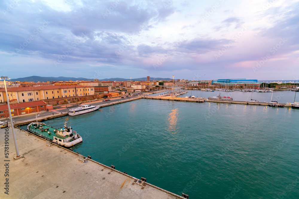 View of the waterfront promenade and cityscape at the cruise port harbor of Livorno, Italy, at dusk.