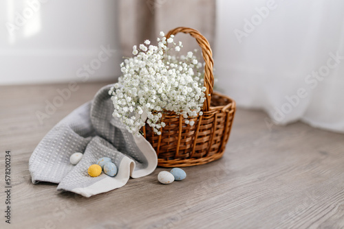 A basket of twigs with white flowers, a towel, blue, yellow, white eggs. Spring Background for Easter