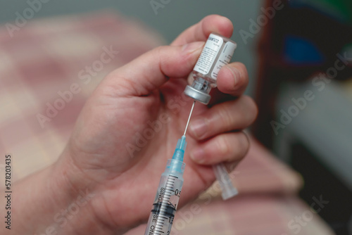 A doctor fills a syringe with rabies vaccine from a vial while at the emergency room. Closeup on hands and process.