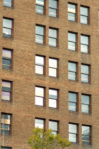Brick building facade in late afternoon shade and visible rows of windows with reflective glass in the downtown city