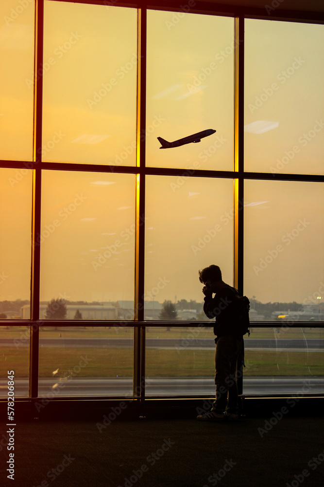 Fototapeta premium Silhouette of a man at the airport with an airplane in the background
