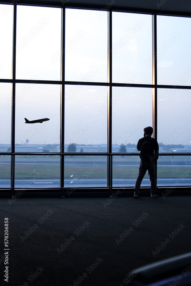 Silhouette of a man standing in front of the window at the airport