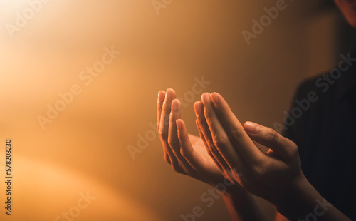 Valokuva Hand praying on orange light bokeh background.