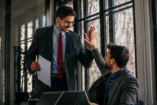 Image of a mid adult manager having a brief meeting with his young associate at the office. They are having lively conversation and they seem to agree about certain points of interest.