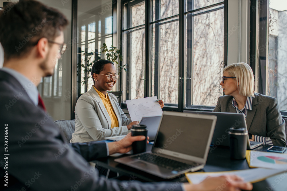 Multi-ethnic group of business persons having a meeting in the office. Businesswoman showing a document Multi-ethnic group of business persons having a meeting in the office. Businesswoman showing a document