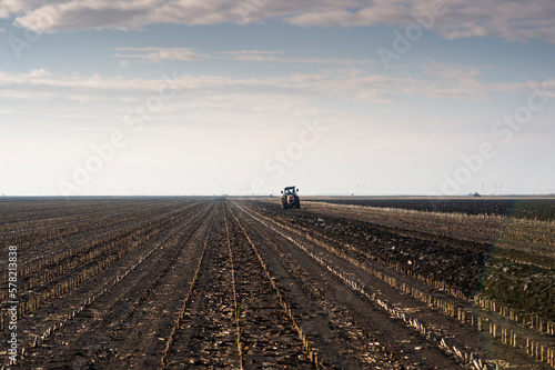 The tractor is working in the field, preparing the soil in the fall after harvesting the corn