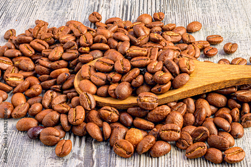 a lot of coffee beans and on top of it a wooden spoon with coffee beans a lot of coffee beans and on top of it a wooden spoon with coffee beans