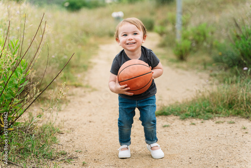 Cute little girl playing with a basketball ball