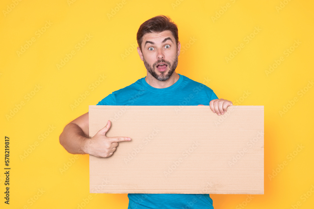 Man holds sign, blank card. Placard ready for your product. Sign to your text. Man showing blank sign board over studio isolated background, pointing finger. Empty blank board. Area for advertising. Man holds sign, blank card. Placard ready for your product. Sign to your text. Man showing blank sign board over studio isolated background, pointing finger. Empty blank board. Area for advertising.
