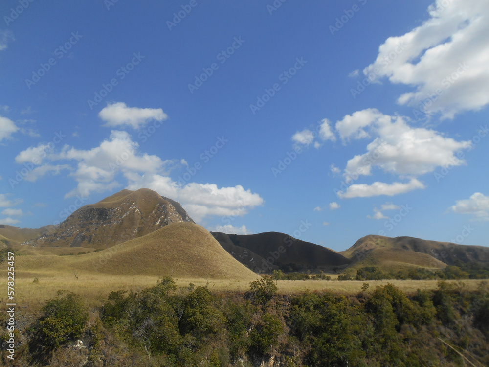 Panorama of beautiful Sumba Island of Indonesia, blue sky, cloudy weather, field grassy in dry season equator country. Rural landscape. Potential tourism. Natural view.