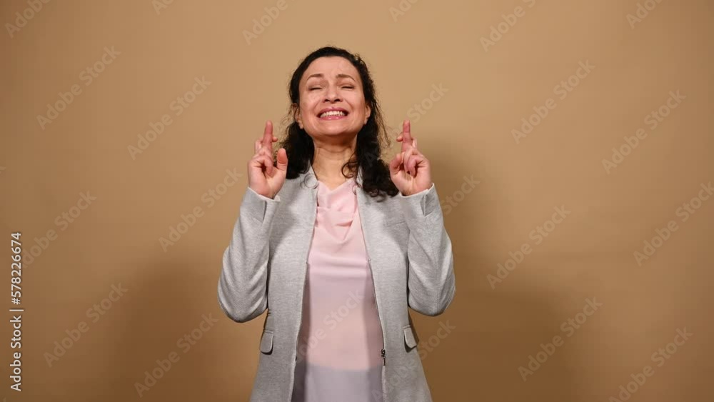 Middle-aged pretty woman crossing fingers, with prayerful hopeful look, makes cherished wishes, hopes her dream comes true, wishing for fortune or good luck, isolated background. People. Emotions Middle-aged pretty woman crossing fingers, with prayerful hopeful look, makes cherished wishes, hopes her dream comes true, wishing for fortune or good luck, isolated background. People. Emotions