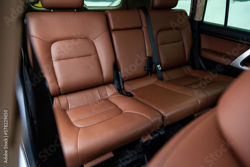 Car inside rear passenger place. Brown interior of prestige modern car. Front seats with steering wheel dashboard. After washing and detailing.