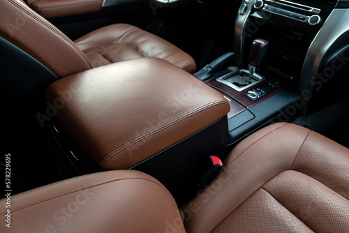 Armrest in the driver's car is upholstered in eco-leather. Beautiful leather car interior design. Luxury leather seats in car. Brown leather seat covers in car.