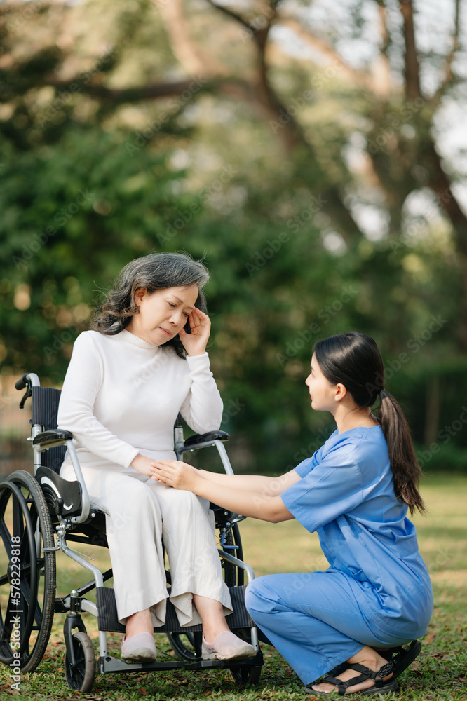 Elderly asian senior woman on wheelchair with Asian careful caregiver. Nursing home hospital garden concept. in sun light Elderly asian senior woman on wheelchair with Asian careful caregiver. Nursing home hospital garden concept. in sun light