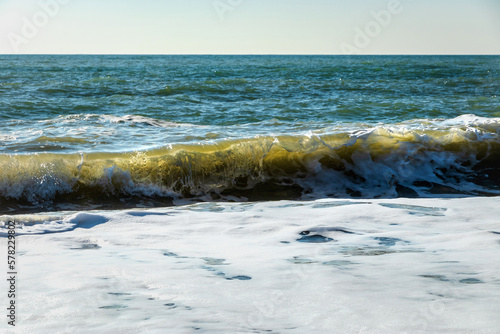 A soft sea wave on a sandy beach. Selective focus. Coastal waves. View of the waves of the Black Sea. Clear wavy sea water. Close-up of a wave on the Black Sea coast.
