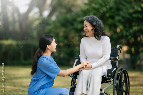 Elderly asian senior woman on wheelchair with Asian careful caregiver. Nursing home hospital garden concept. in sun light © Nuttapong punna