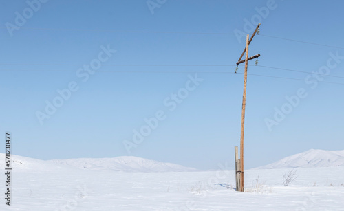 power line in snowy field with blue clear sky
