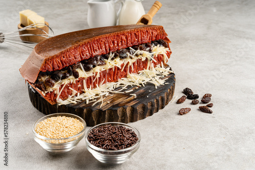 Martabak manis or terang bulan is indonesian sweet pancake, with red color and filled with chocolate chips, cheese, fruit jam, butter and peanut on concreate background. photo