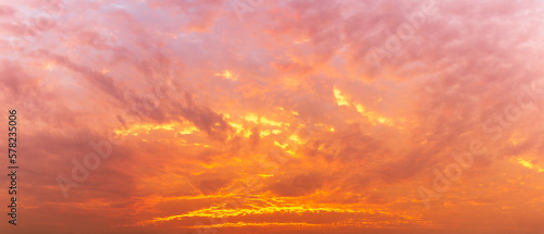 Photo of the golden hour sky, fluffy clouds covered the sky, panoramic image, orange tones, natural phenomenon background.