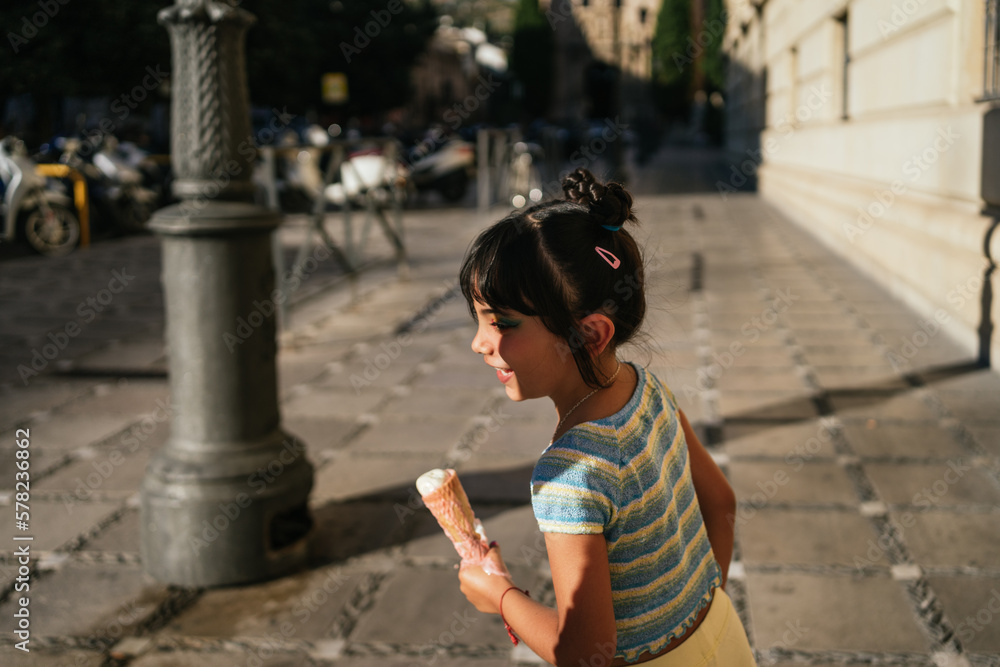 Child running around in the street with an ice cream in her hands