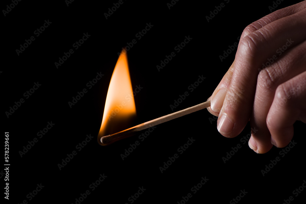 A burning match in hand. Hand with a burning match in the dark.	
